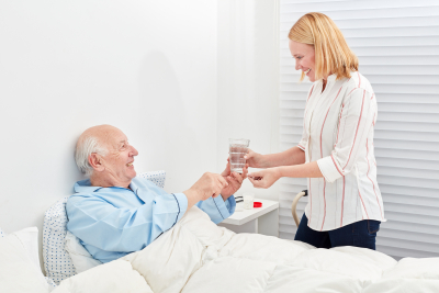 woman gives senior a tablet and a glass of water