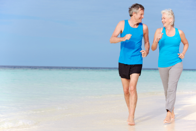 senior couple running on beautiful beach smiling