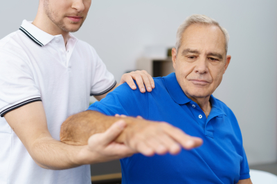 therapist massaging senior man's arm
