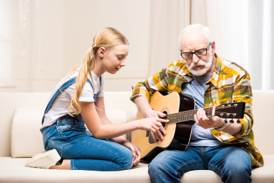 senior man and his cute little granddaughter playing acoustic guitar